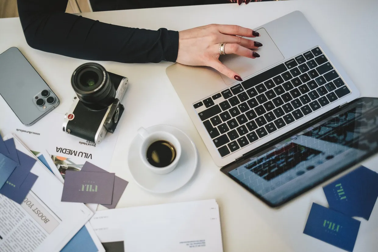 Laptop, Kamera und Visitenkarten von VILU Media auf einem Tisch